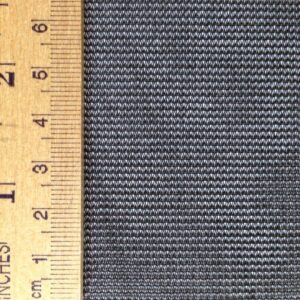 Close-up of a textured dark fabric alongside a wooden ruler, showing measurements. Useful for illustrating fabric characteristics in a textile context.