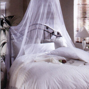 A canopy bed with a white mosquito net drapes over a neatly made bed, creating a serene and stylish sleeping space in a softly lit room.