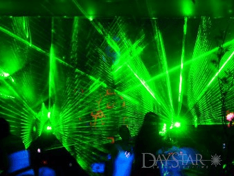Vibrant green laser lights illuminate a lively dance floor, creating an energetic atmosphere for a nightlife event.