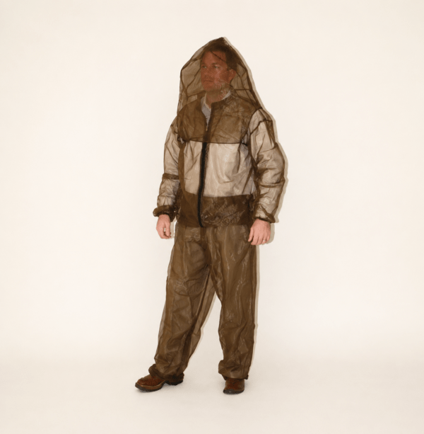 Man standing in a translucent brown protective suit with a hood. The outfit is designed for insect protection, highlighting safety gear for outdoor activities.