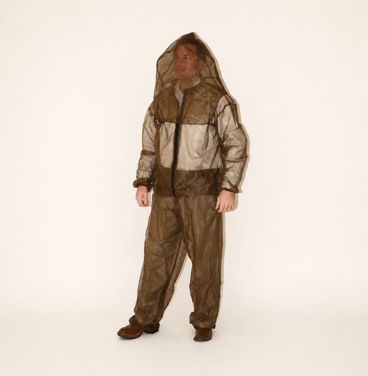 Man standing in a translucent brown protective suit with a hood. The outfit is designed for insect protection, highlighting safety gear for outdoor activities.