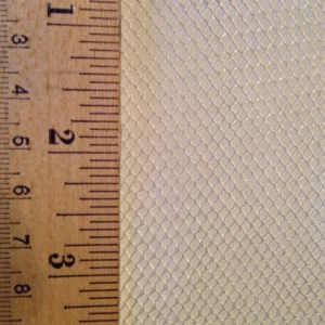 Close-up of a textured, hexagonal mesh material alongside a ruler measuring up to 3 inches, illustrating its size and pattern for textile reference.